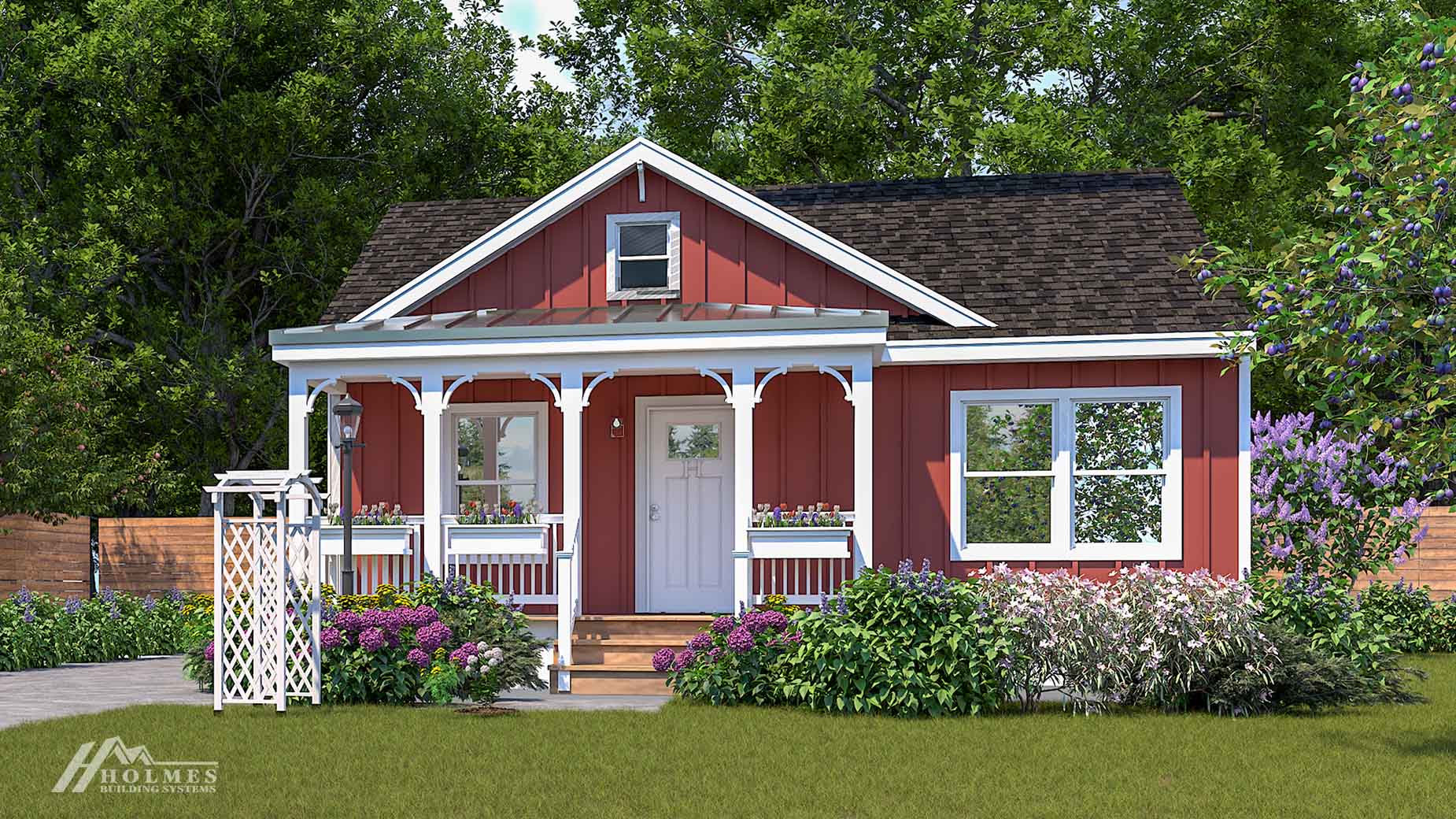 A charming small red modular home with a front porch, white trim, flowers, and a green lawn, surrounded by trees.