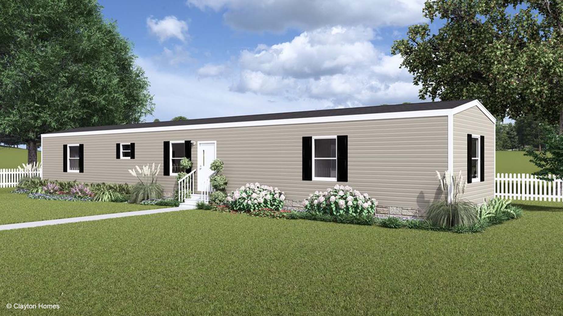 Charming single-story beige manufactured home with black shutters, surrounded by a lush lawn, vibrant flowers, and a classic white picket fence.