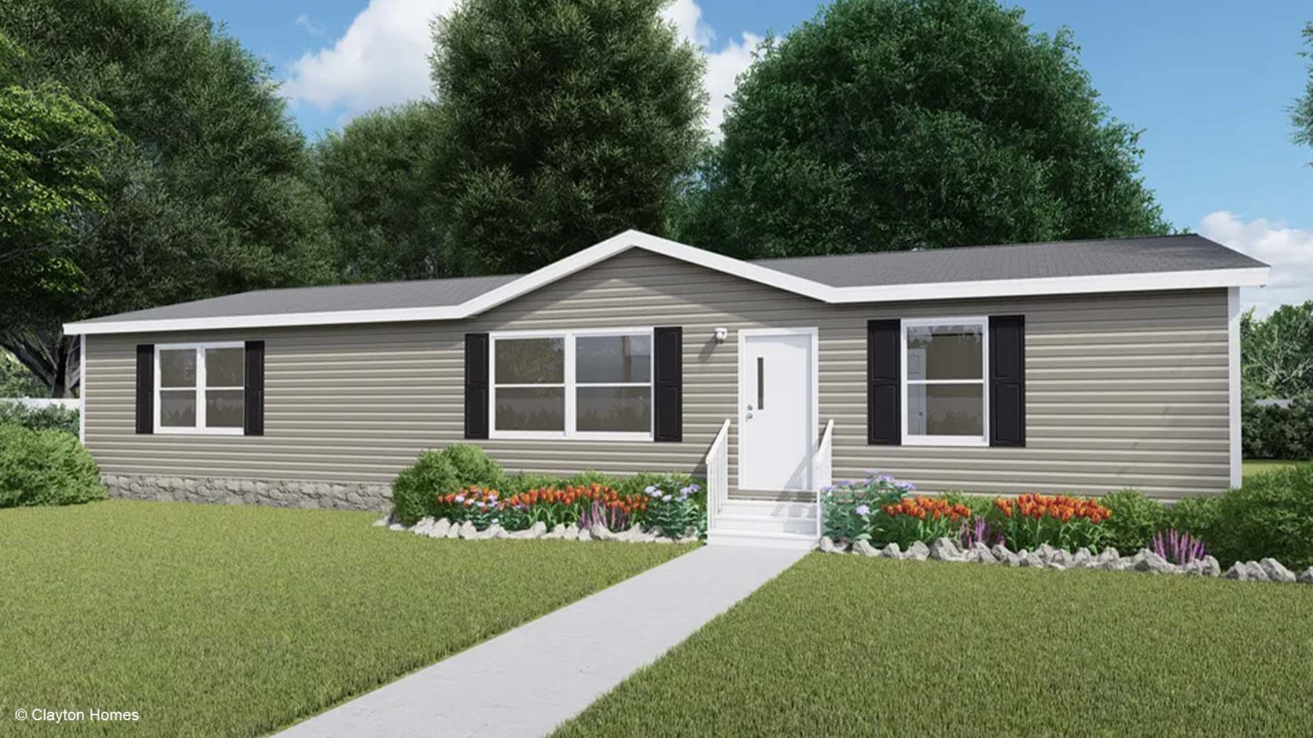 Single-story manufactured home with beige siding, black shutters, and a front garden filled with colorful flowers and shrubs.